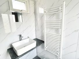 A bathroom with a sink and towel radiator at Cwt Tyddyn Shepherd's Hut in Cefn Brith near Cerrigydrudion