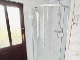 A bathroom with a shower and door at Cwt Tyddyn Shepherd's Hut Cefn Brith near Cerrigydrudion
