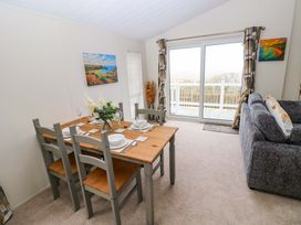 A dining area with a table and chairs at Wernlas Lodge Oxwich