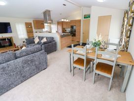 A living room with a dining area and kitchen at Wernlas Lodge in Oxwich