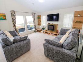 A living room with two sofas and a television at Wernlas Lodge in Oxwich