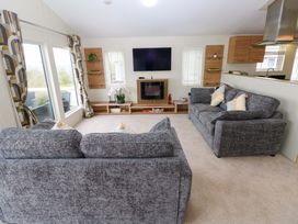 A living room with sofas and a television at Wernlas Lodge in Oxwich