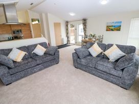 A living room with sofas and a dining area at Wernlas Lodge in Oxwich