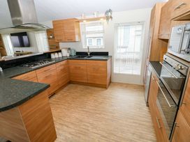 A kitchen with cabinets and sink at Wernlas Lodge in Oxwich