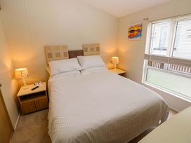 A bedroom with a bed and bedside table at Wernlas Lodge in Oxwich