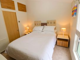 A bedroom with a bed and nightstand at Wernlas Lodge in Oxwich