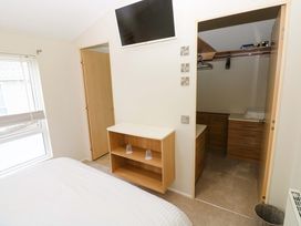 A bedroom with a bed and a wardrobe at Wernlas Lodge in Oxwich