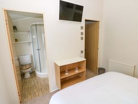 A bedroom with a bathroom doorway and storage at Wernlas Lodge in Oxwich