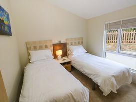 A bedroom with twin beds and a nightstand at Wernlas Lodge in Oxwich