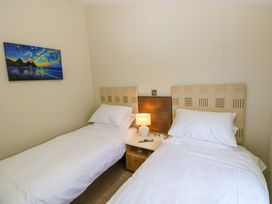 A bedroom with two single beds and a bedside table at Wernlas Lodge in Oxwich