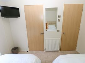 A bedroom with a TV, mirror, and two doors at Wernlas Lodge in Oxwich