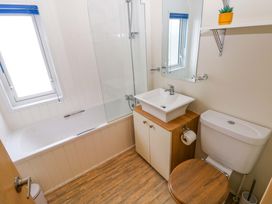 A bathroom with a bathtub, sink, and toilet at Wernlas Lodge in Oxwich