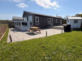 A patio area with a table and chairs at Wernlas Lodge in Oxwich