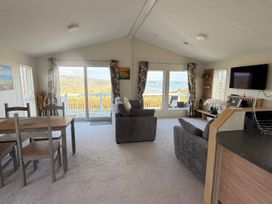 A living room with a sofa and dining table at Wernlas Lodge in Oxwich
