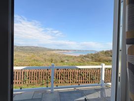A view of hills and water from a window at Wernlas Lodge Oxwich