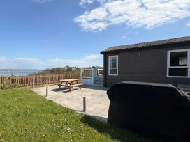 A patio with a picnic table and grill at Wernlas Lodge Oxwich