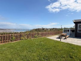A garden with a table and chairs overlooking the water at Wernlas Lodge in Oxwich