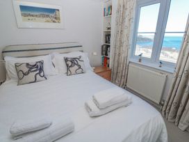 A bedroom with a bed and a window overlooking the sea at 21 Compass Point in Carbis Bay