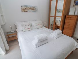 A bedroom with a bed, bedside table, and wardrobe at 21 Compass Point in Carbis Bay