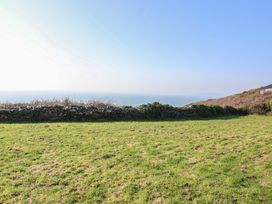 An outdoor view of grass and a stone wall overlooking the ocean at The Cabin 