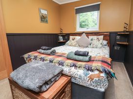 A bedroom with a bed and shelves at Owls Nest Lodge South Molton