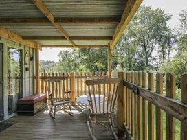 A porch with two rocking chairs and a table at Owls Nest Lodge in South Molton