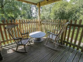 An outdoor seating area with rocking chairs and a table at Owls Nest Lodge in South Molton