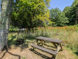 A table and benches with a fire pit in a grassy area at Owls Nest Lodge in South Molton