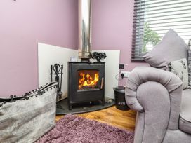 A living room with a stove and fire at Hedgehogs Lodge South Molton