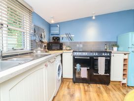 A kitchen with a sink, oven, washing machine and refrigerator at Hedgehogs Lodge South Molton