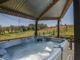 A hot tub under a canopy with a view of fields at Hedgehogs Lodge South Molton