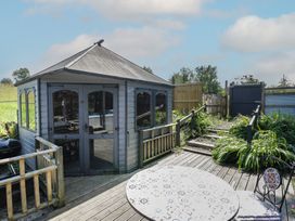 A gazebo with decking and table in the garden at Hedgehogs Lodge South Molton