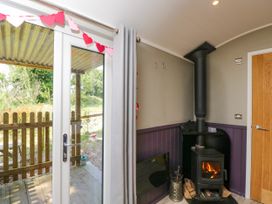 A living room with a stove and door leading outside at Valley View Shepherd's Hut in South Molton