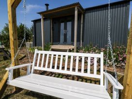 A swing bench with a building in the background at Hares Hideaway Shepherd's Hut South Molton