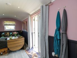 A living room with a bed and a door at Hares Hideaway Shepherd's Hut in South Molton