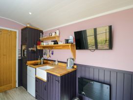 A kitchen with a sink and shelves at Hares Hideaway Shepherd's Hut in South Molton