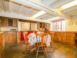 A kitchen with wooden cabinets and a table with chairs at The Farmhouse in Keswick