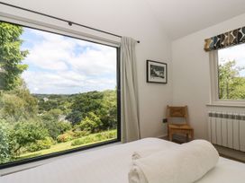 A bedroom with a view and a chair at Wood Meadow in Helston