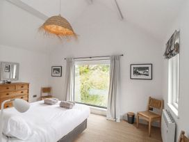 A bedroom with a bed and window at Wood Meadow in Helston