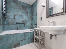 A bathroom with a bathtub and wall-mounted sink at Wood Meadow in Helston