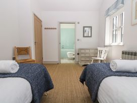 A bedroom with two beds and a door leading to a bathroom at Wood Meadow in Helston