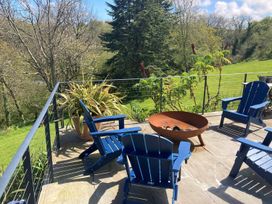 An outdoor patio with blue chairs and a fire pit at Wood Meadow in Helston