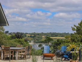 An outdoor area with a dining table and chairs overlooking a water view at Wood Meadow in Helston