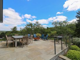 An outdoor patio with a table and chairs at Wood Meadow in Helston