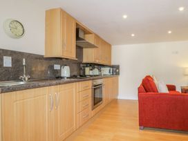 A kitchen with wooden cabinets and a red sofa at Farmhouse Cottage in Keswick