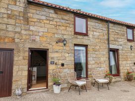 An outdoor area with a stone wall and seating at Wren's Nest in Lealholm