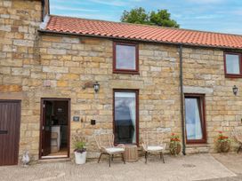 An outdoor area with stone walls and furniture at Wren's Nest in Lealholm
