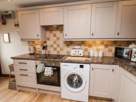 A kitchen with a washing machine, oven, and microwave at Wren's Nest in Lealholm