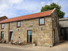 A stone building with windows and outdoor seating at Swallow Cottage in Lealholm