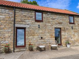 An outdoor area with stone walls and chairs at Swallow Cottage Lealholm